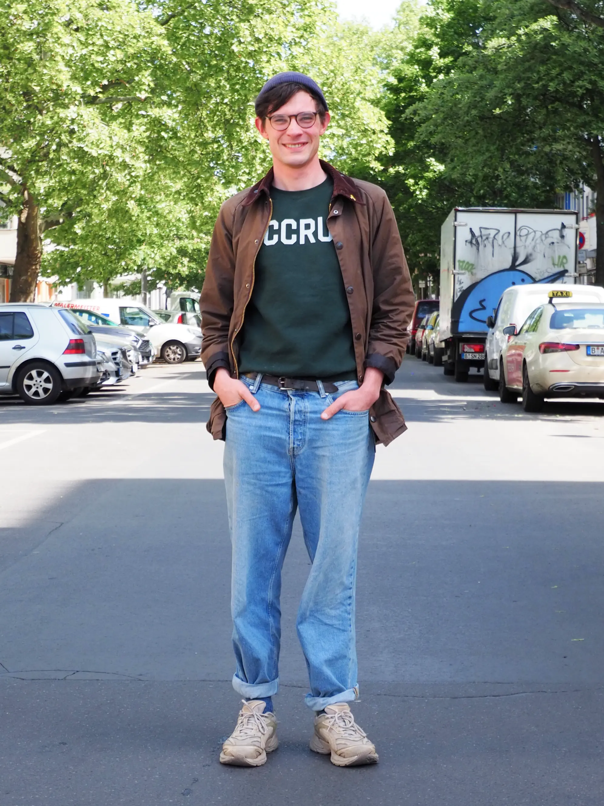 Junge Mann mit CCRU Sweater, Mütze und Brille am Lachen auf Straße