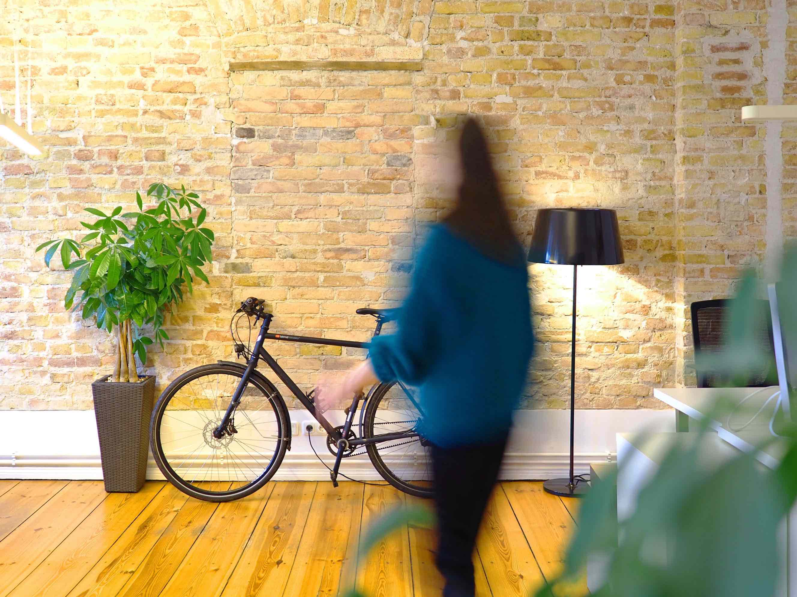 Fahrrad stehend an einer Backsteinmauer. Person läuft durch Bild.