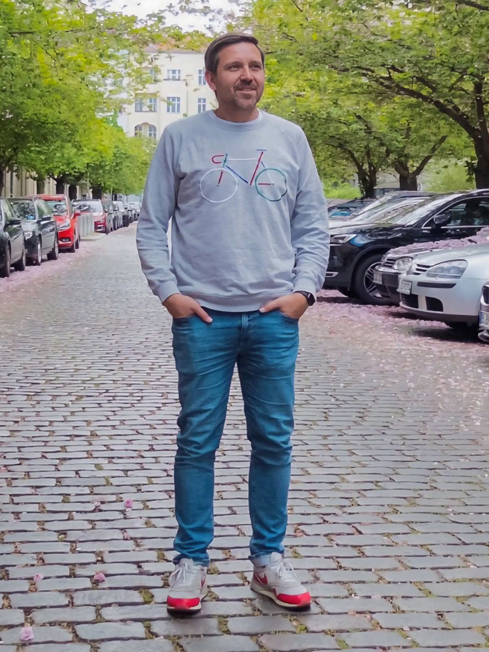 Mann mit grauem Sweater auf Kopfsteinpflaster