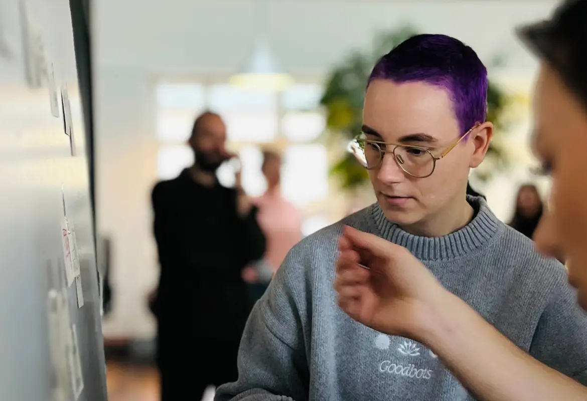 Zwei Personen in schwarzen T-Shirts schauen stehen vor schwarzem Hintergrund (s/w)