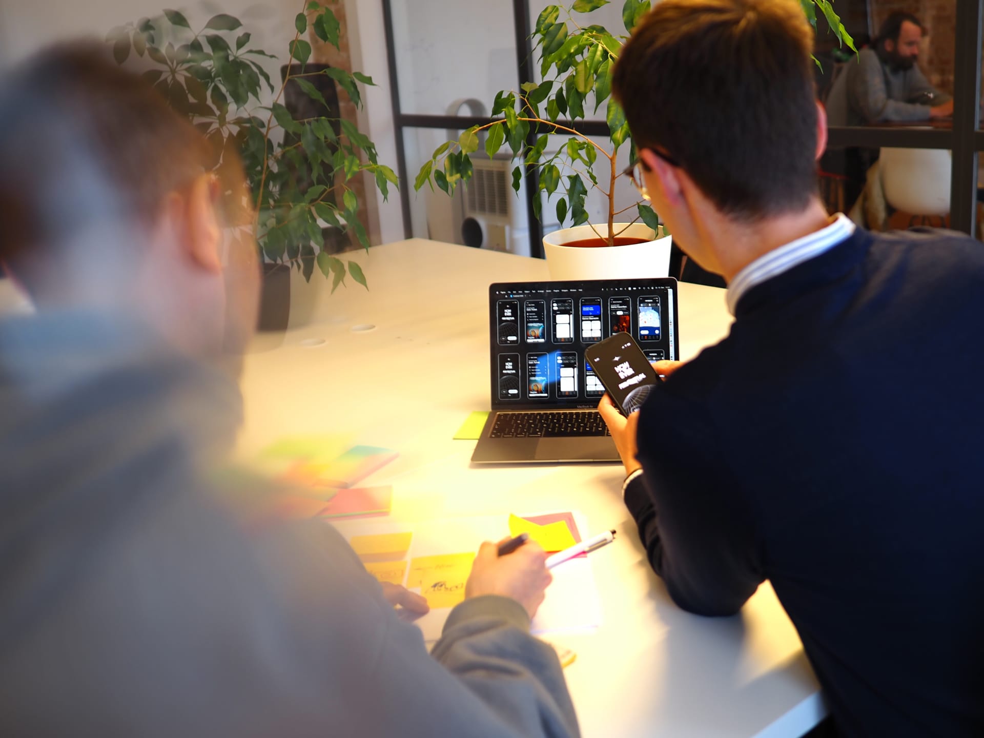 Zwei Personen sitzen an einem Tisch mit einem Laptop und testen einen App Prototypen.