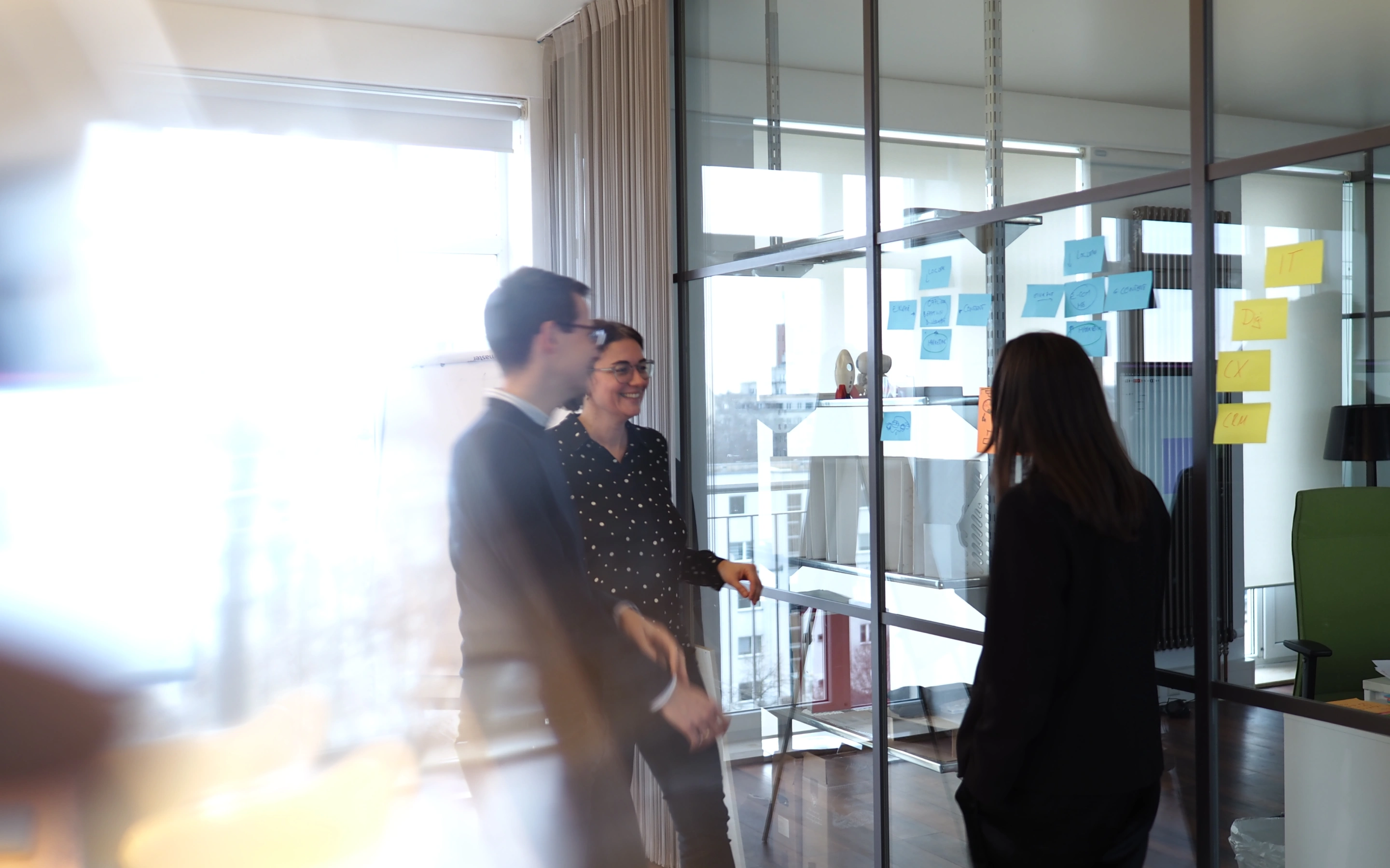 Drei Personen unterhalten sich in einem lichtdurchfluteten Büro