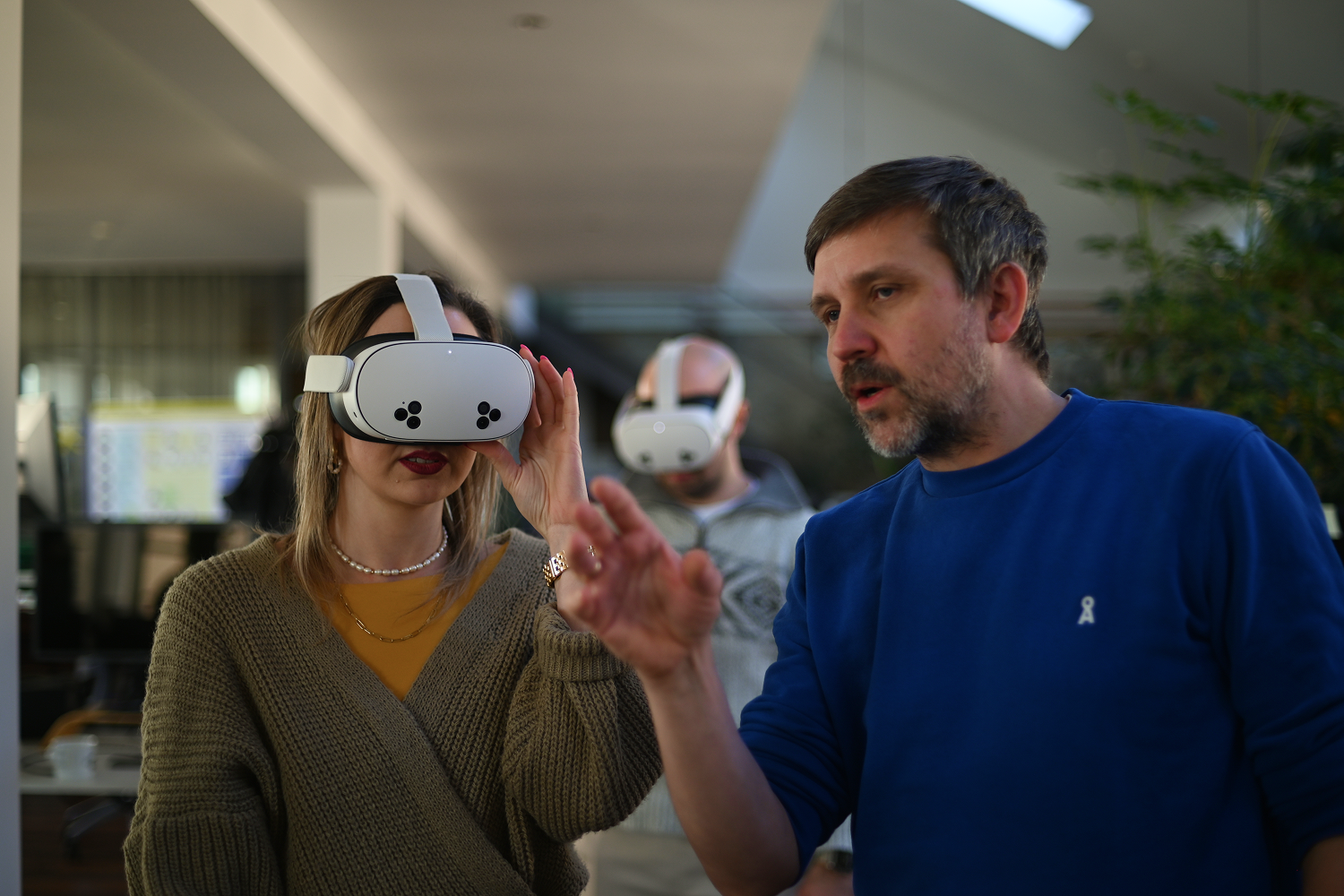 Ein Mann erklärt einer jungen Frau die Funktionsweise einer handelsüblichen VR/MR-Brille