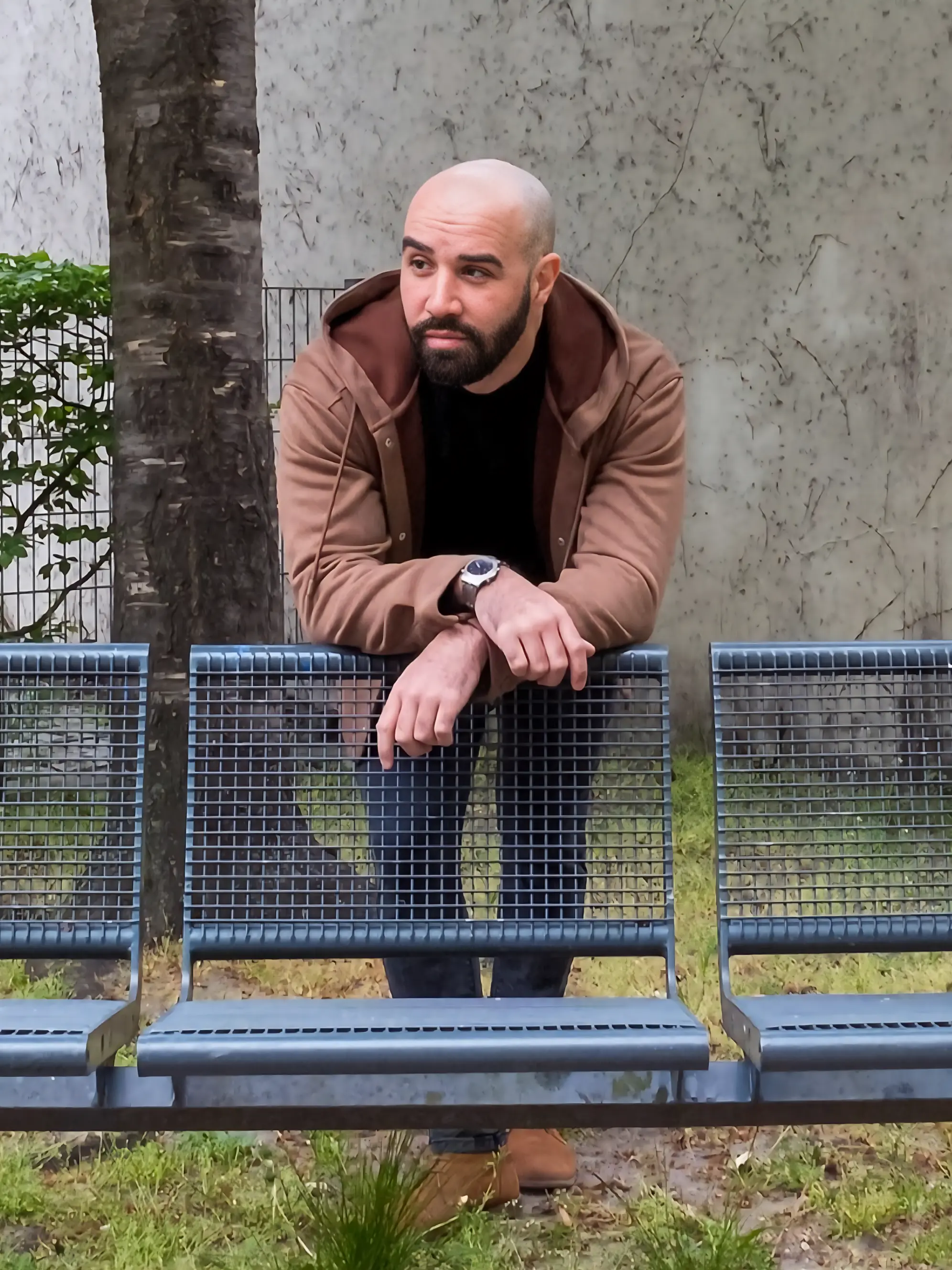 Mann lehnt lässig über Parkbank