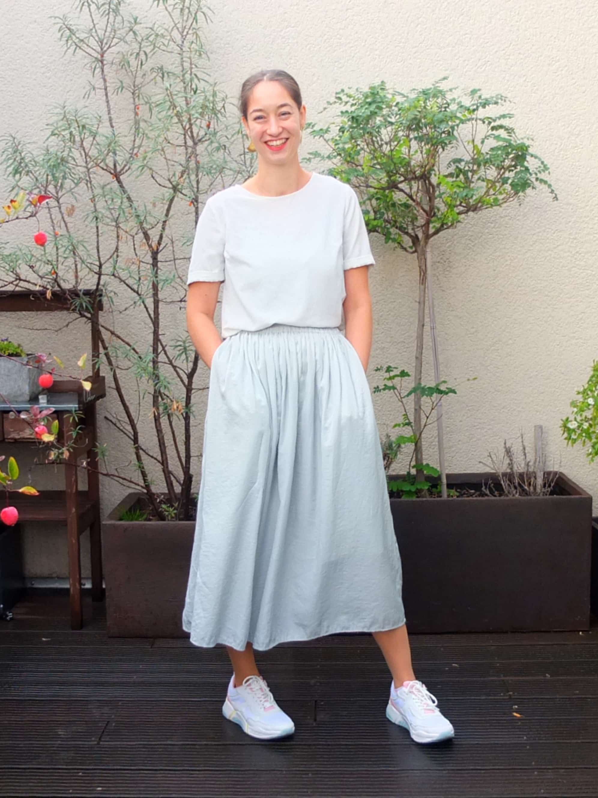 A woman in a light blue skirt and white shirt is standing on a roof terrace.