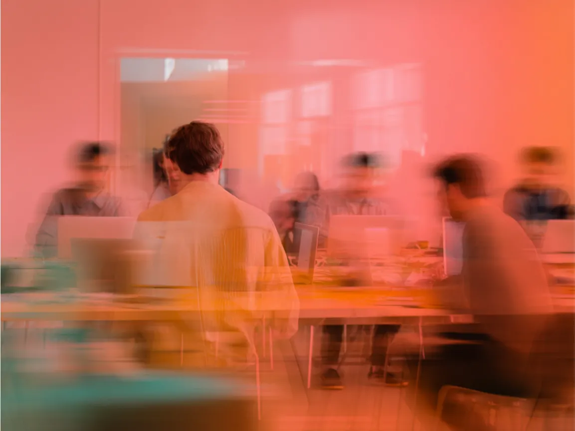 Menschen arbeiten an Laptops in einem offenen Büro, durch Bewegungsunschärfe entsteht ein dynamischer, energiegeladener Eindruck von Zusammenarbeit und Kreativität.