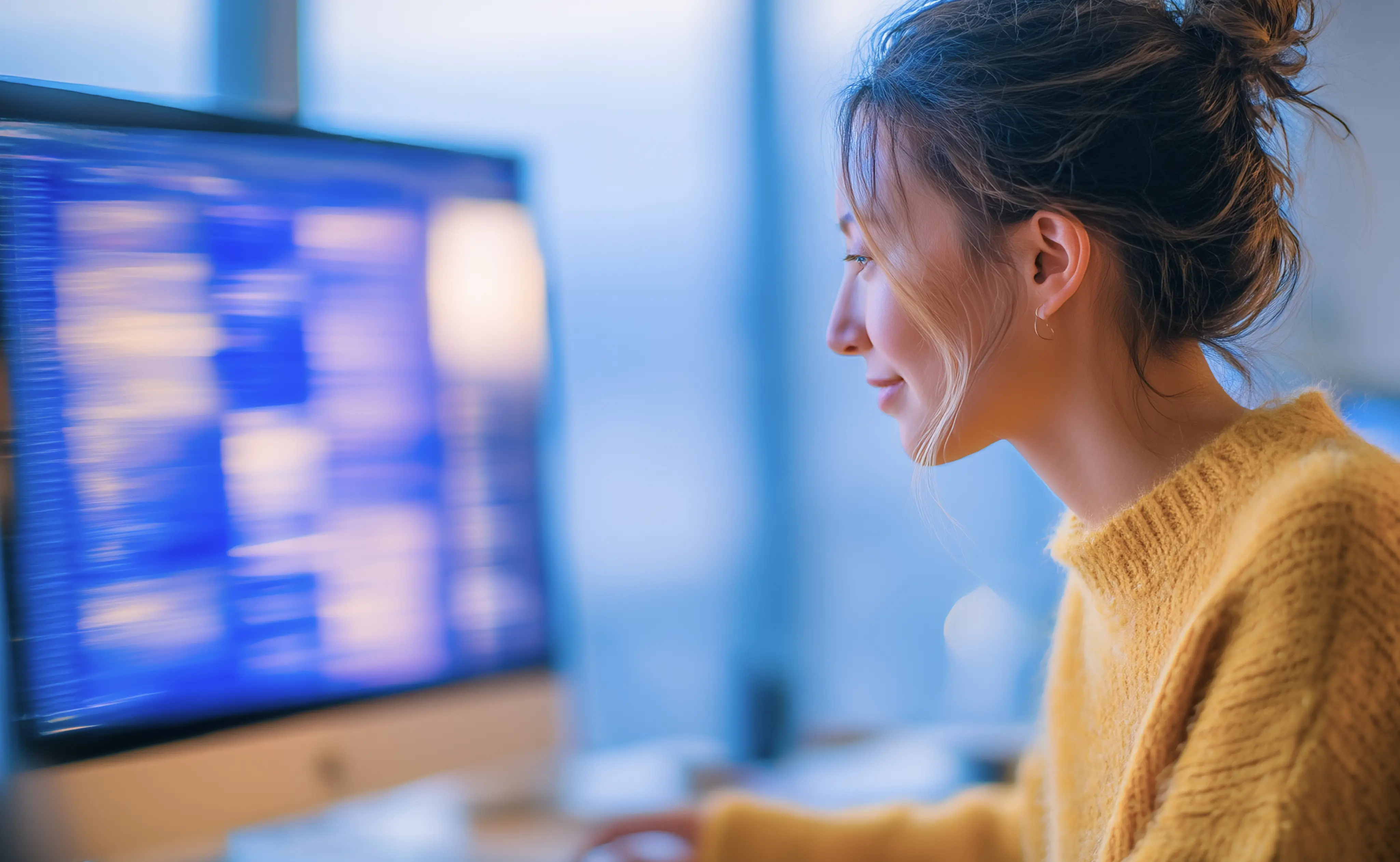 Frau sitzt lächelnd vor einem Computer